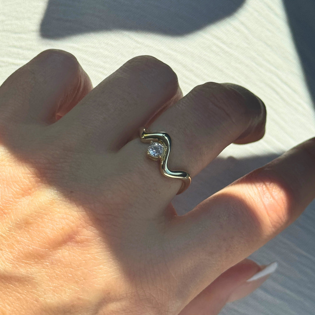 Gold Wavy Ring with a Diamond on A Woman's Finger by Kataleya Jewellery