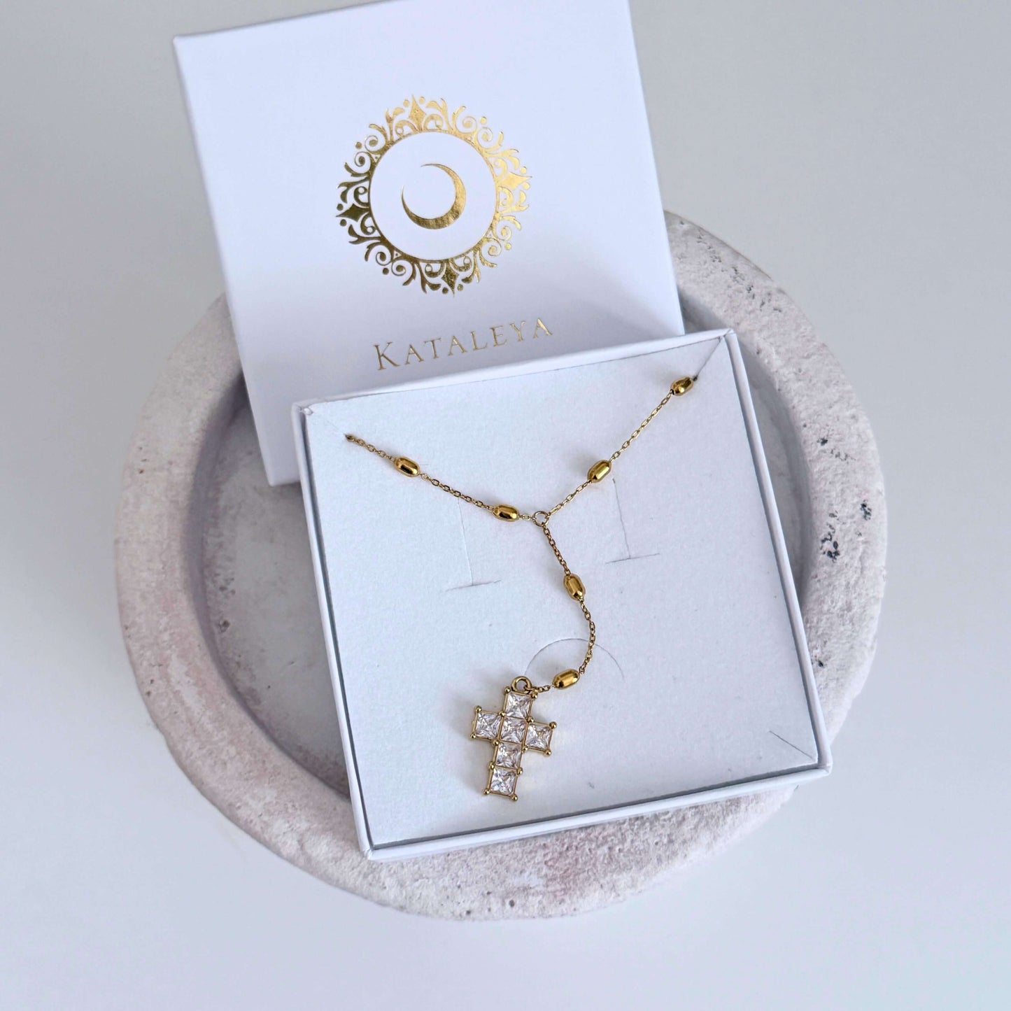 Veyra Cross Lariat Necklace displayed in elegant packaging, showcasing the gold cross drop design with sparkling zircon details.