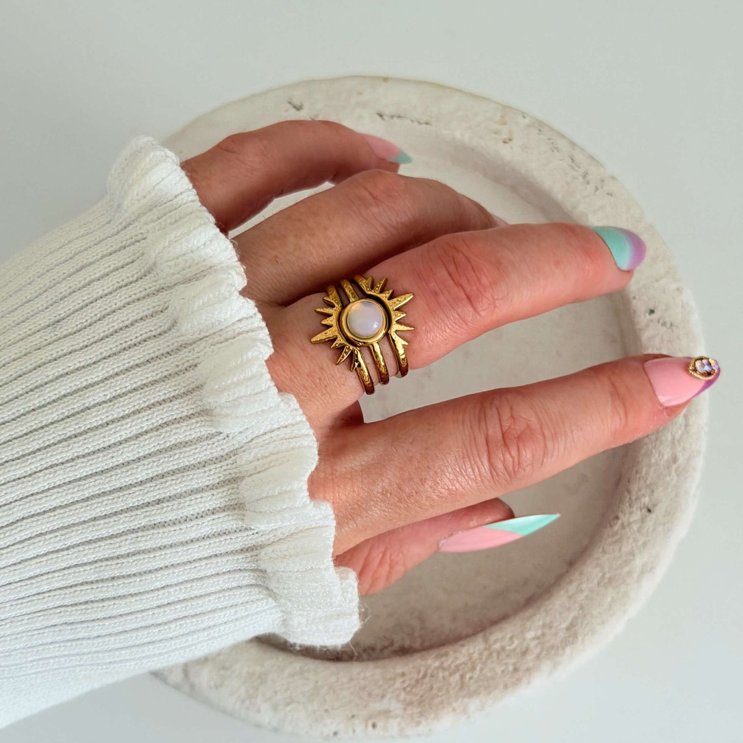 Hand displaying Gold Sun & Opalite Stacking Rings from the Solara Ring Set, featuring a sun design and opalite stone.