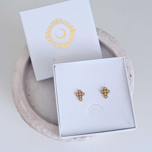 Gold Crystal Cross Earrings in elegant packaging with a logo on a neutral background.