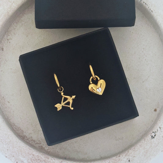 Cupid Hoop Earrings with golden charms: a bow and heart with cubic zirconia, symbolizing love and connection.