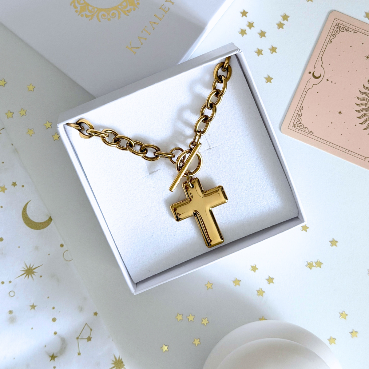 Cassia Cross Necklace displayed in a box featuring a gold cross on a thick chain.