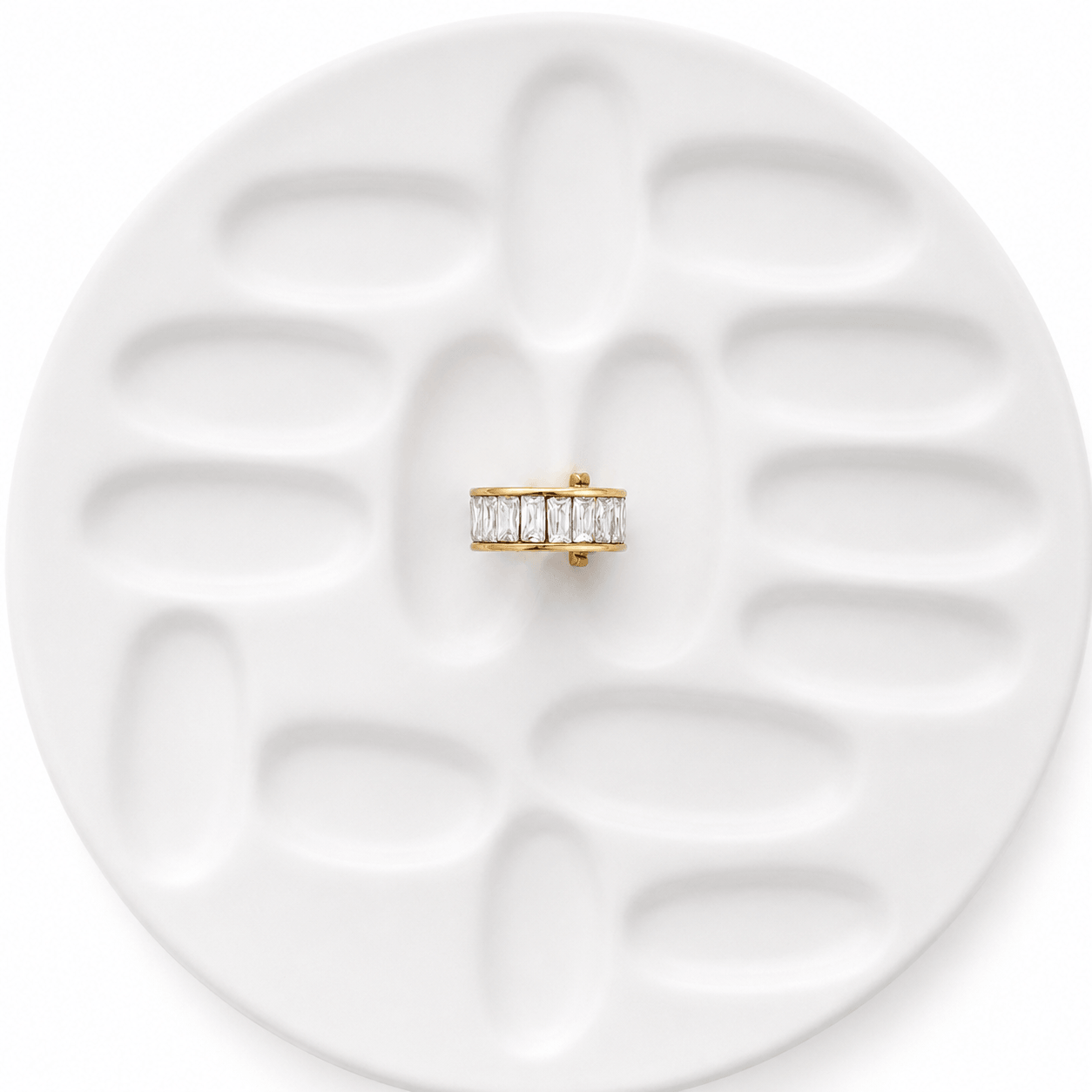 Veyra Crystal Ear Cuff displayed on a textured white plate, featuring Gold Zircon Ear Cuff with princess-cut stones.