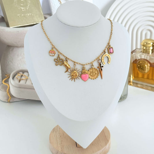Dainty Charm Necklace featuring gold and pink charms including a cupcake, flower, and sun on a display bust.