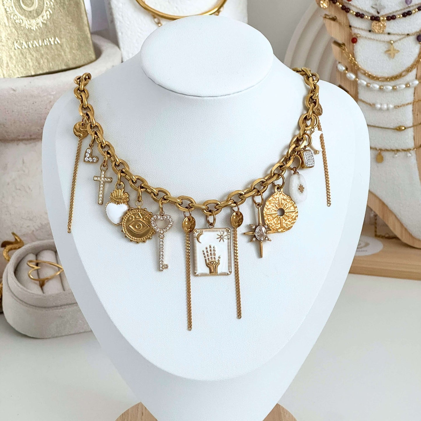 Gold necklace with various charms on a white mannequin bust by Kataleya Jewellery
