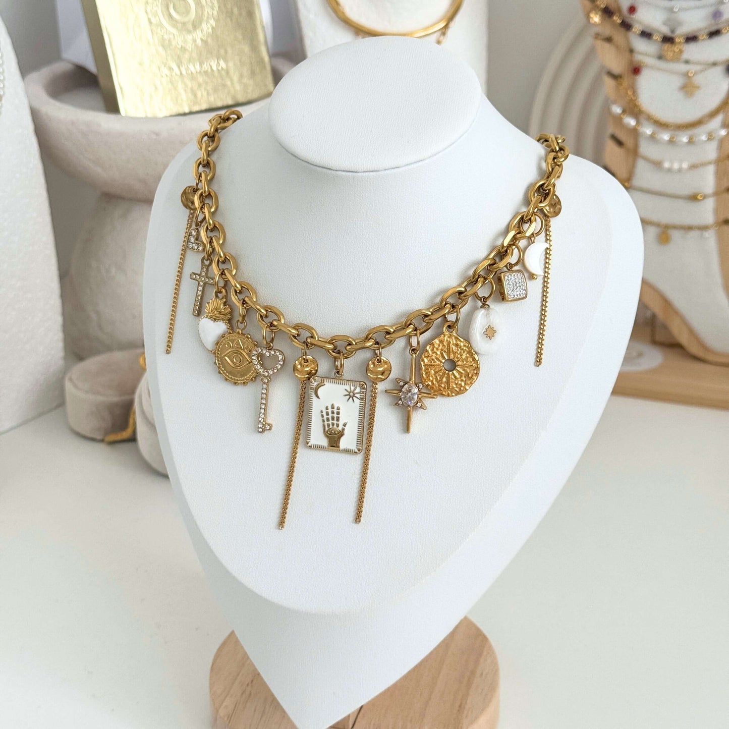 Gold necklace with charms on a white mannequin bust by Kataleya Jewellery