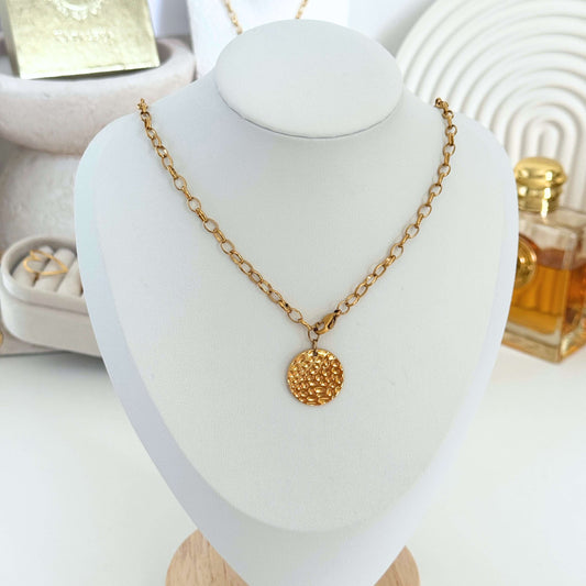 Gold Disc Necklace showcasing a textured gold disk on a display stand, highlighting elegant waterproof jewelry.