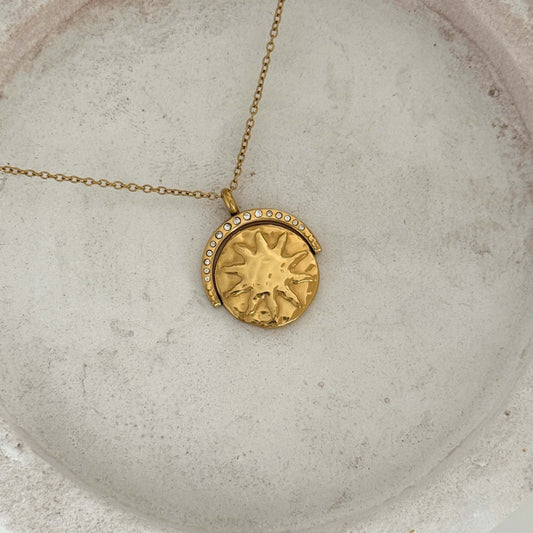 Spinner Sun Necklace featuring a gold chunky pendant with sun design and zirconia stones on a delicate chain.