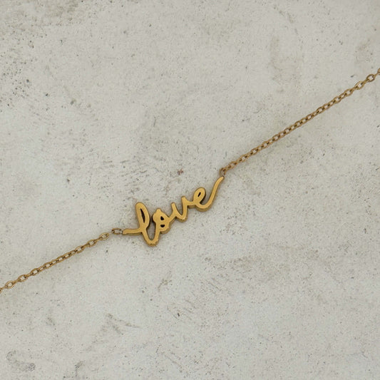 Love Word Necklace in gold script on a delicate chain, perfect for layering or wearing alone as a symbol of affection.