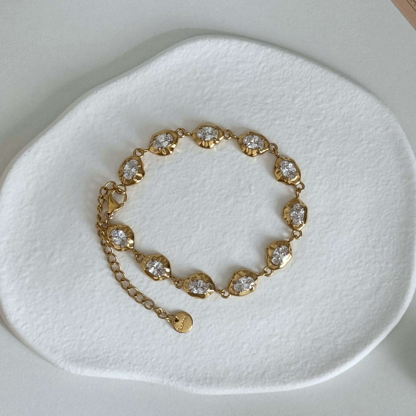 Kora Waterproof Bracelet featuring gold design and shimmering zircon stones on a textured surface.
