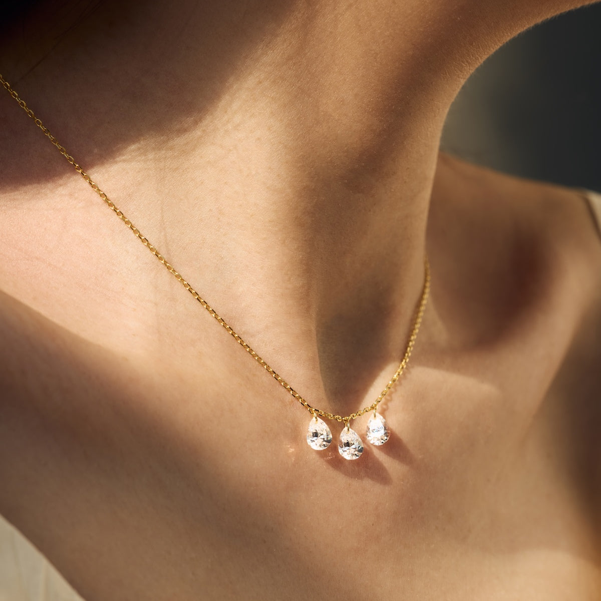 Gold Seraphine Trinity necklace with three droplet pendants on a person's neck - Kataleya Jewellery