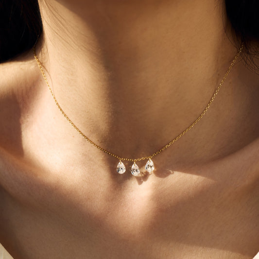 Gold Seraphine Trinity necklace with teardrop-shaped pendants on a person's neck - Kataleya Jewellery