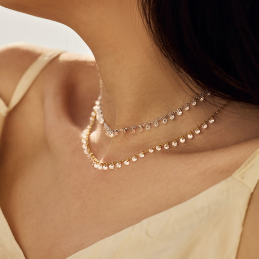 Close-up of a woman wearing a delicate diamonds Seraphine Aurora necklace with a blurred background by Kataleya Jewellery