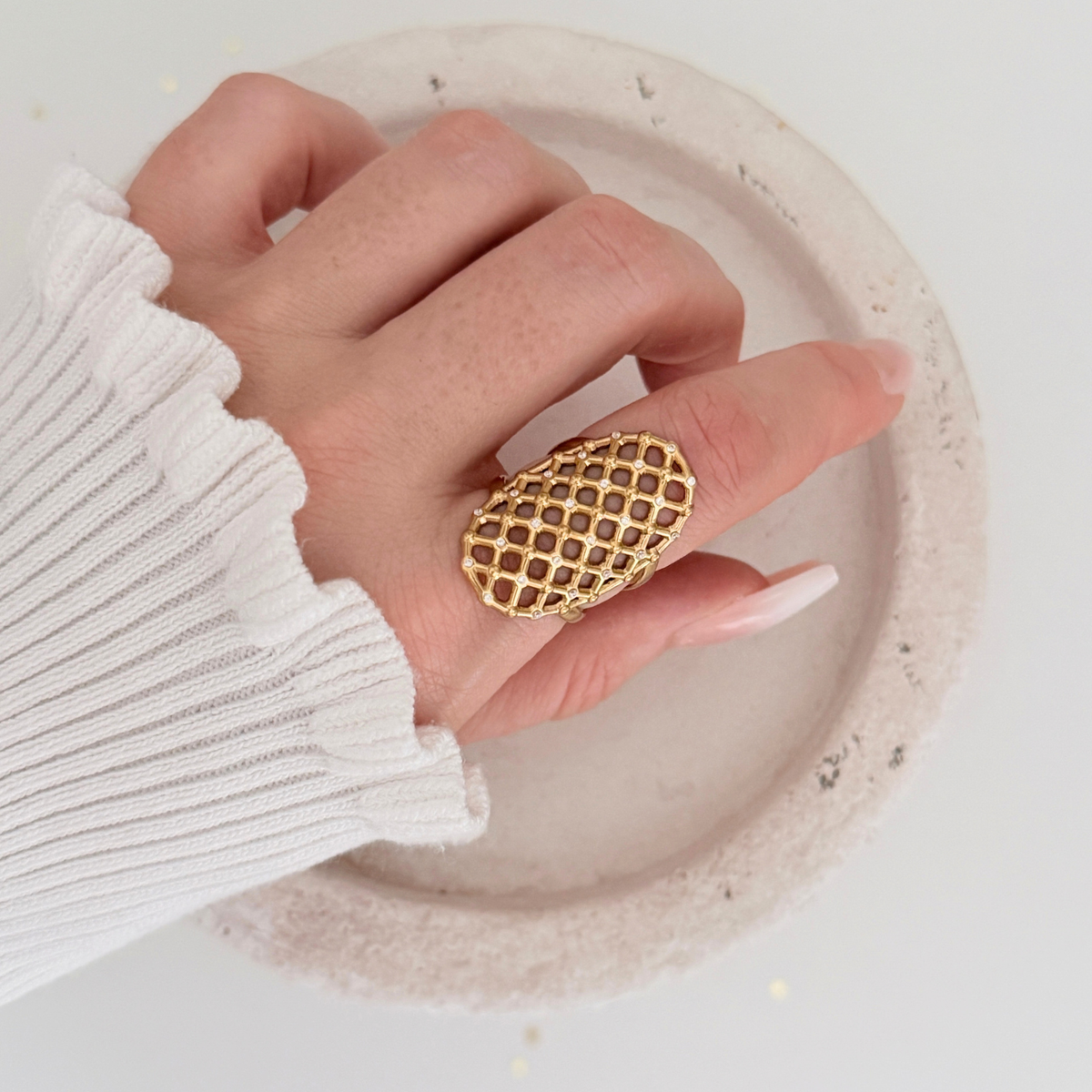 Hand wearing the Vela Lattice Ring, showcasing the golden lattice design and cubic zirconia details.