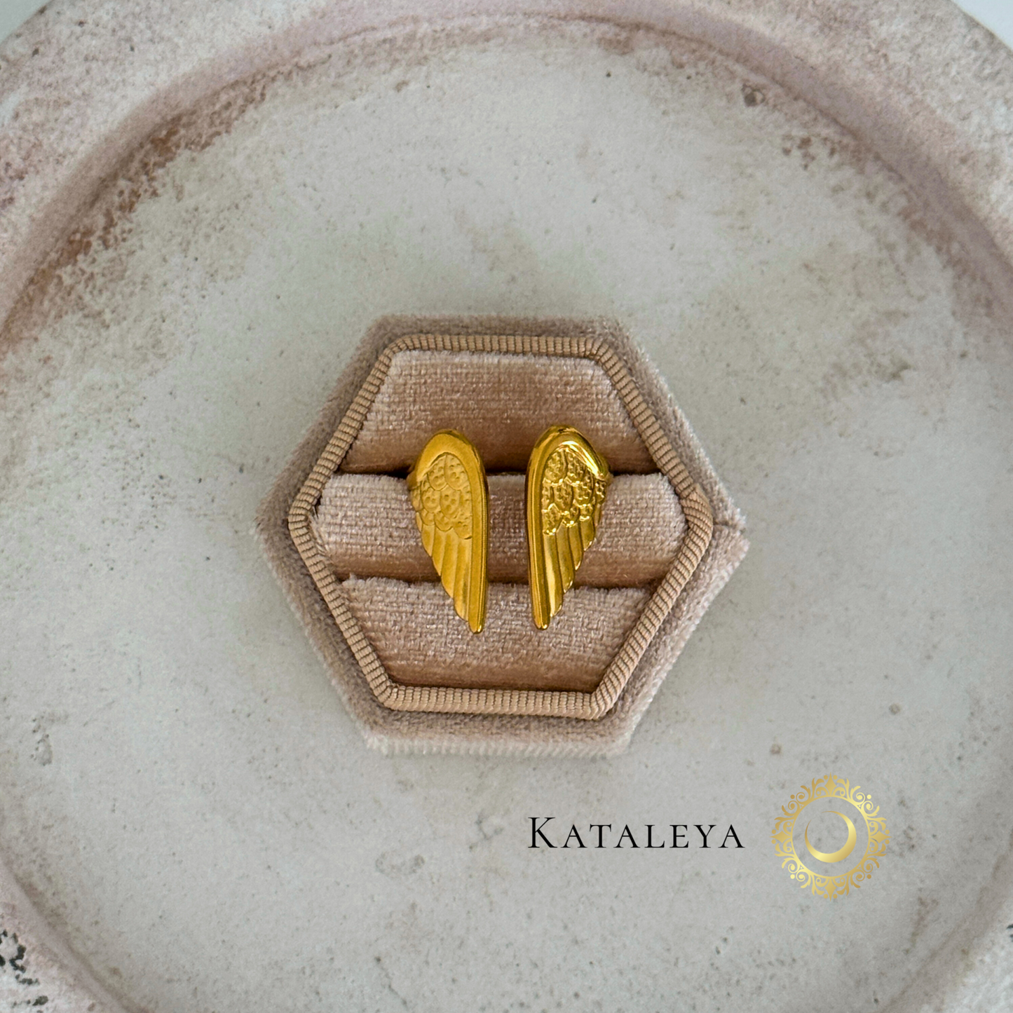 Winged Goddess Ring displayed on a hexagonal ring holder, showcasing intricate wing design in gold finish.