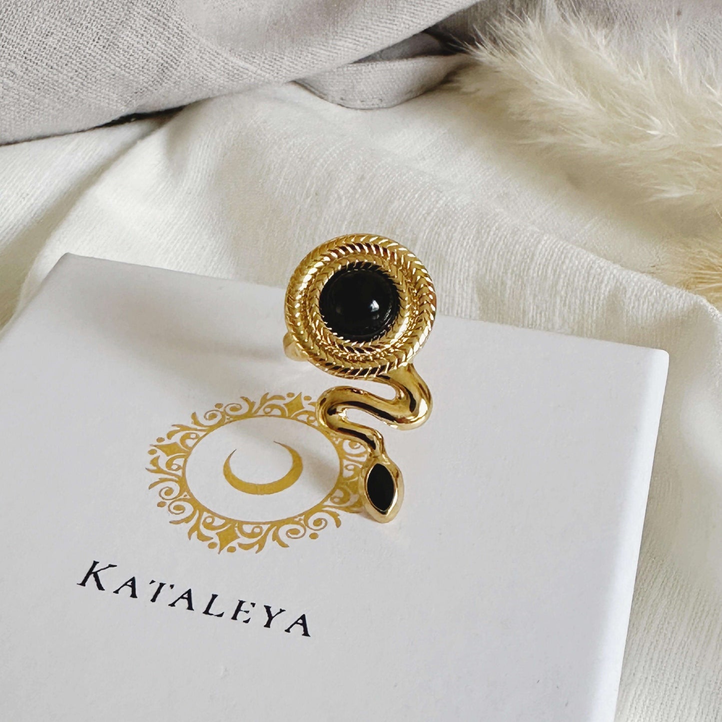 Chic gold plated Snake Agate Ring with black agate stone, displayed on a Kataleya branded box.
