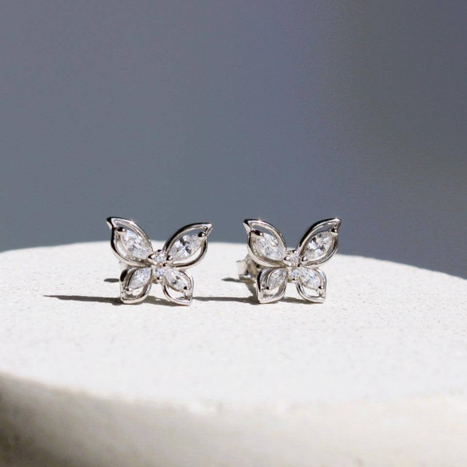 Elegant butterfly stud earrings with shimmering zirconia, set on a light background for a luxurious style.