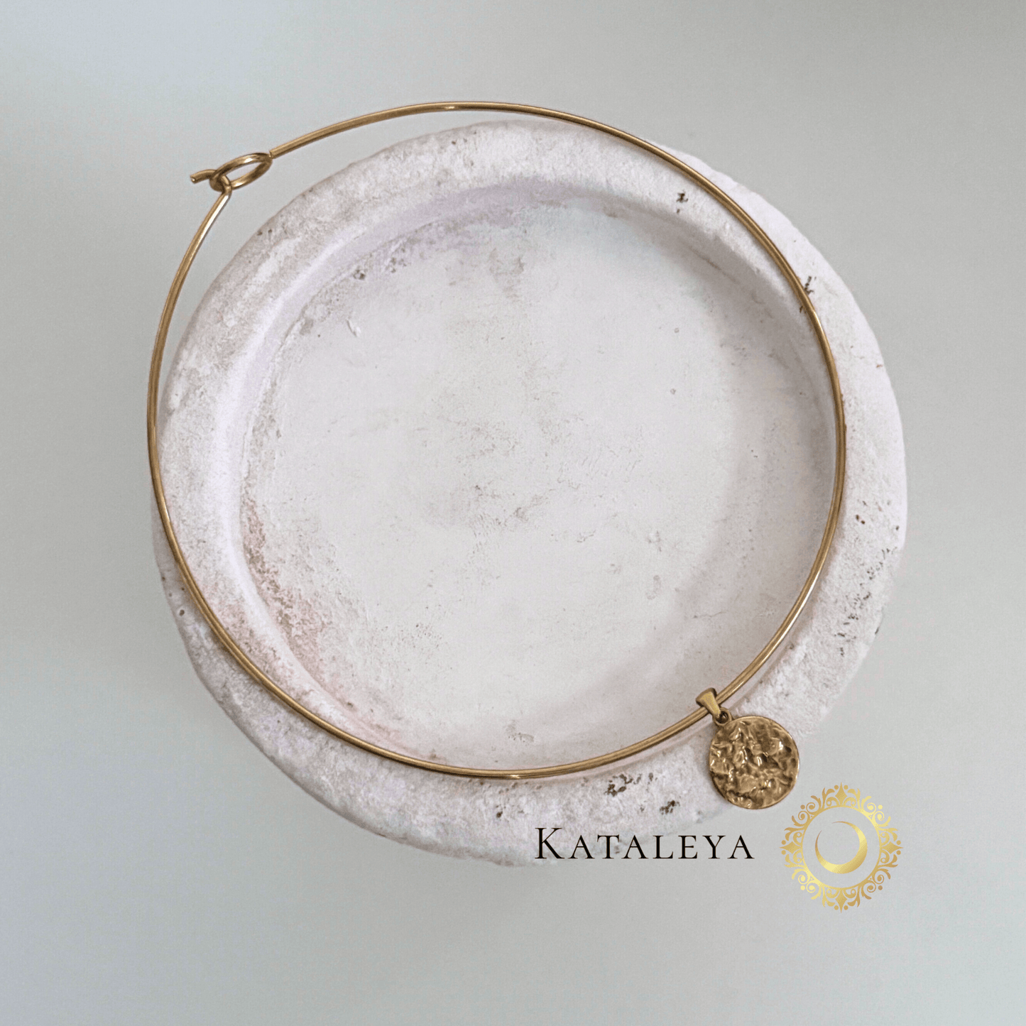 Coin Wire Choker featuring a sleek gold wire design and textured coin pendant on a minimalist plate.