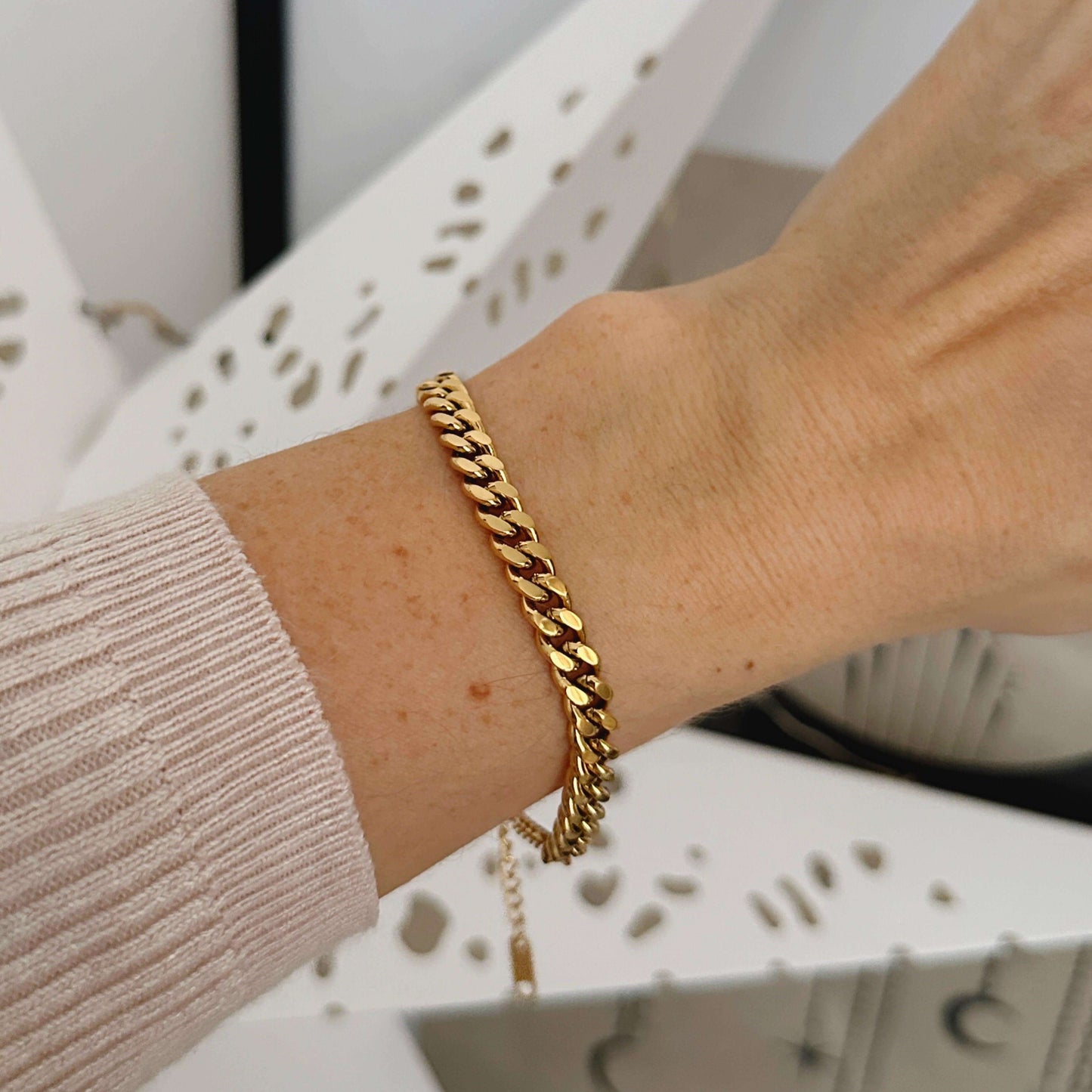Elegant gold Cuban chain bracelet worn on a wrist, showcasing its bold design and luxurious finish.