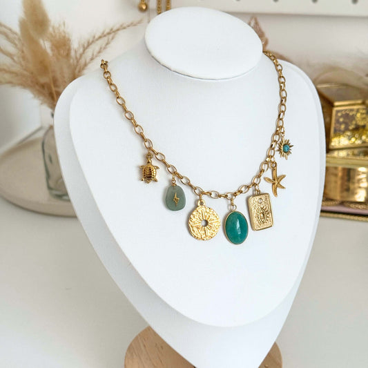 Multi-charm Necklace featuring gold charms and green stones on a display bust.