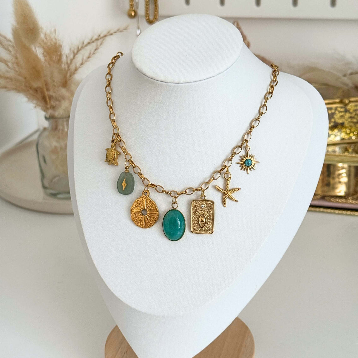 Multi-charm Necklace featuring gold charms and turquoise accents displayed on a jewellery bust.