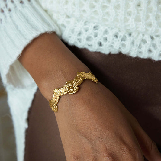 Close-up of a woman's wrist wearing a Spirit Eagle cuff bracelet, showcasing intricate eagle design in gold.