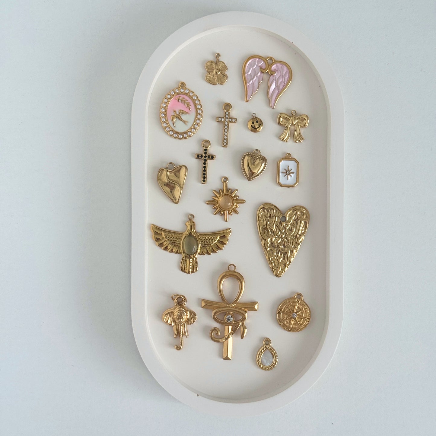 Collection of gold charms on a white trinket tray by Kataleya Jewellery on a white bakcground