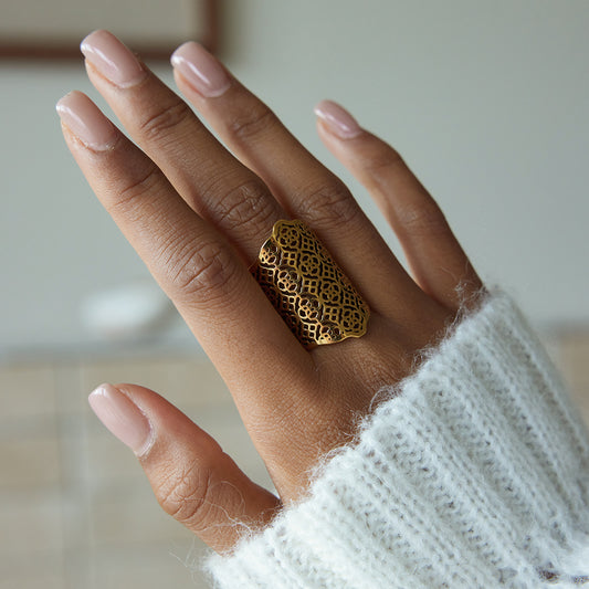 Hand wearing a Statement Filigree Ring, featuring intricate gold filigree design and soft sweater background.