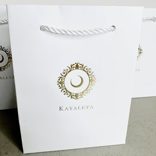 Kataleya small gift bag in white kraft paper with stylish twisted cord handles and elegant gold logo.