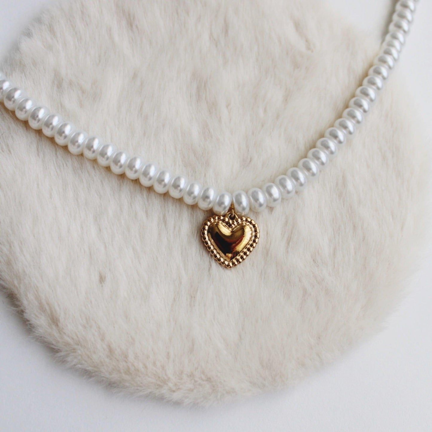Heart pearl necklace featuring a delicate gold heart pendant on a soft fur background.