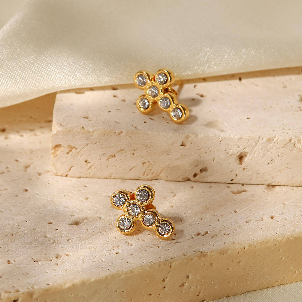 Gold Crystal Cross Earrings displayed on a neutral stone surface showcasing their sparkling design.