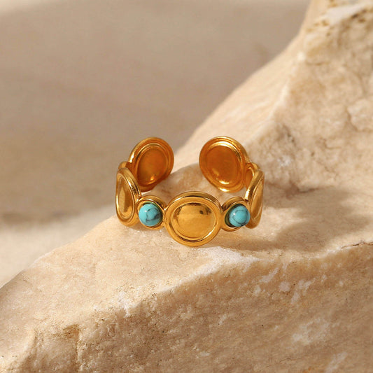 Gold Turquoise Adjustable Ring showcasing smooth gold discs and vibrant turquoise stones on a natural stone surface.