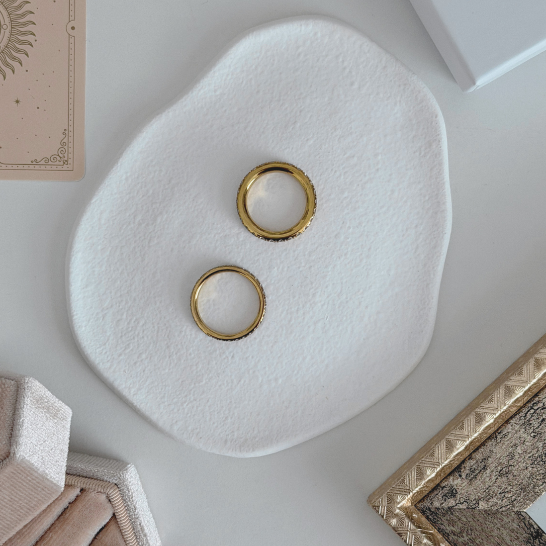 Scarlett Eternity Ring displayed with another gold ring on a white ceramic plate.