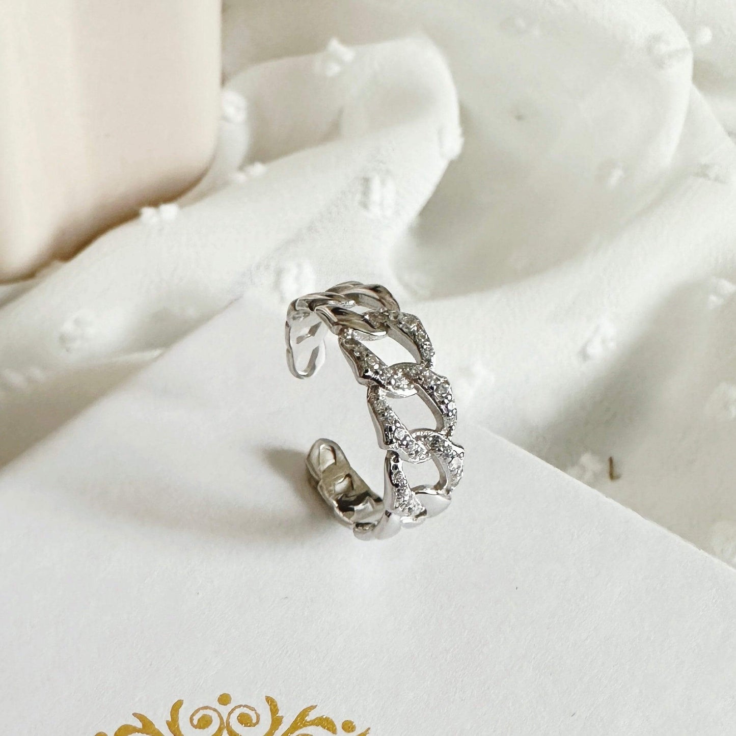 Simone Silver Jewellery Set adjustable chain ring with sparkling accents on soft fabric background.