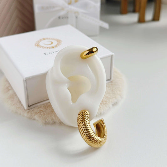 Stylish white earring display holder featuring a chunky gold hoop earring in a snake design.