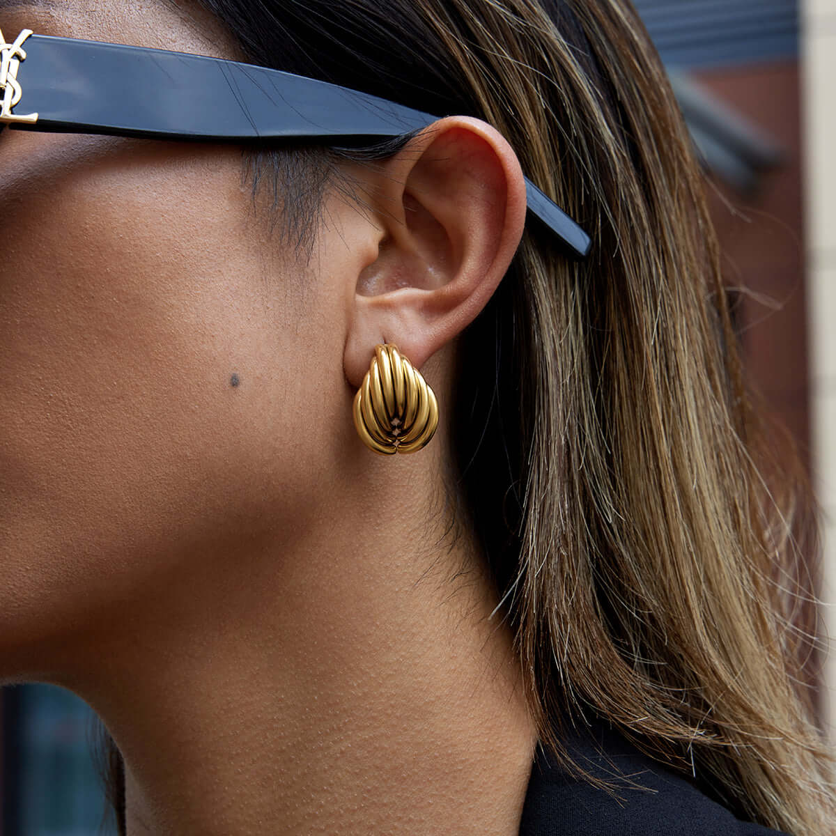 Close-up of a woman wearing Chunky Teardrop Earrings made of gold plated stainless steel.