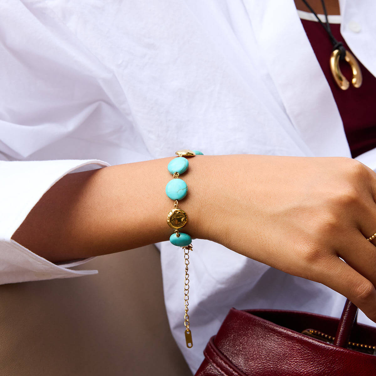 Gold Turquoise Bracelet worn on a wrist, featuring vibrant turquoise stones and polished gold discs.