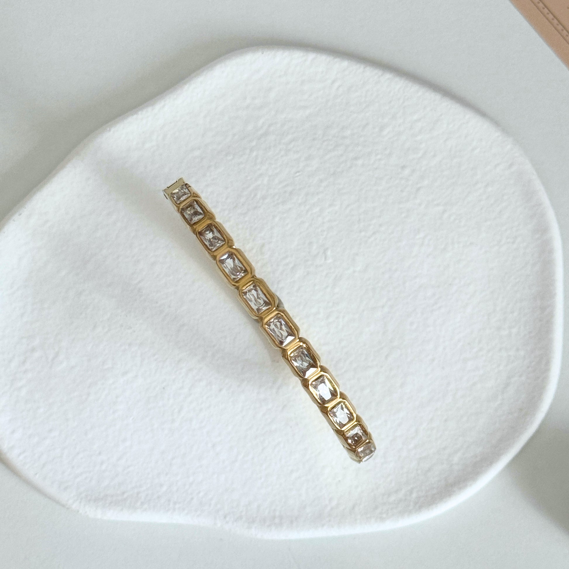Veyra – Waterproof Gold Zircon Bangle with rectangular zircon stones on a textured surface.