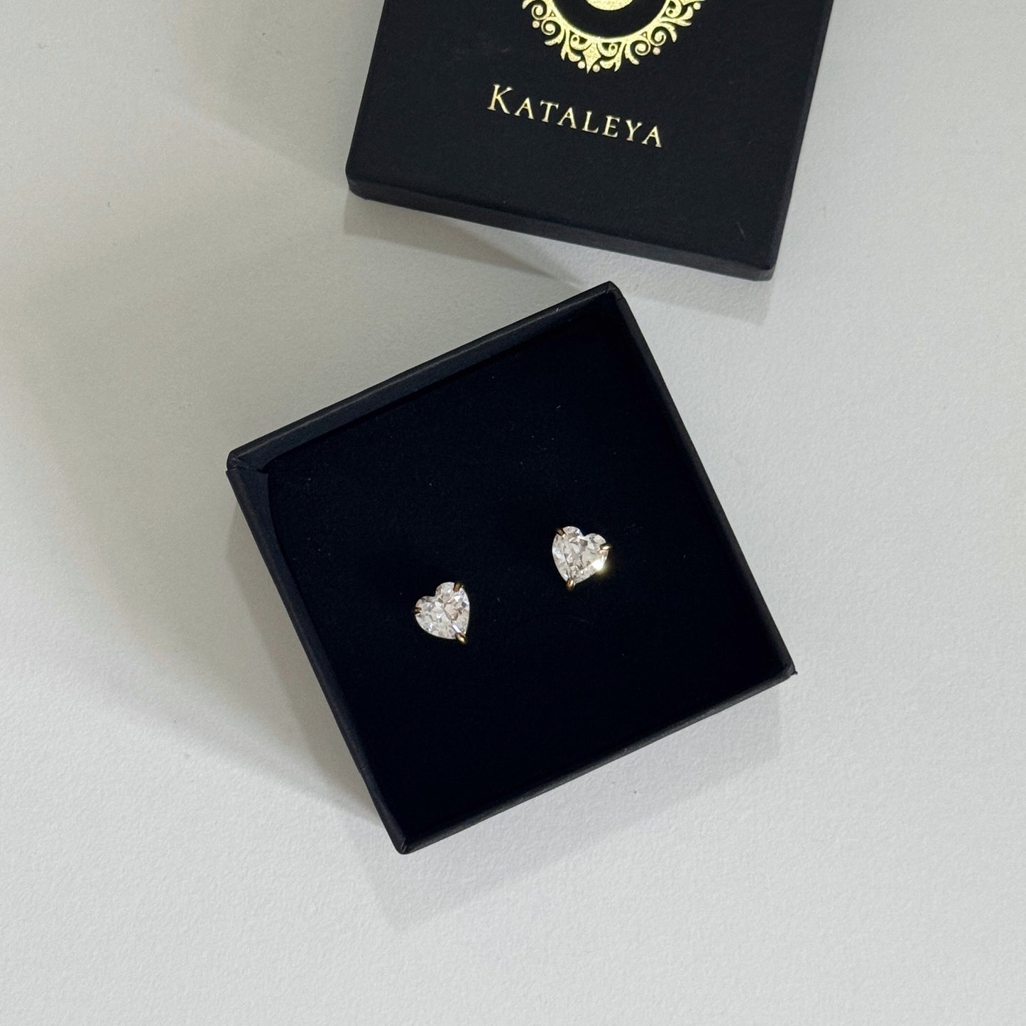 Heart stud earrings with cubic zirconia in a black jewelry box by Kataylea.