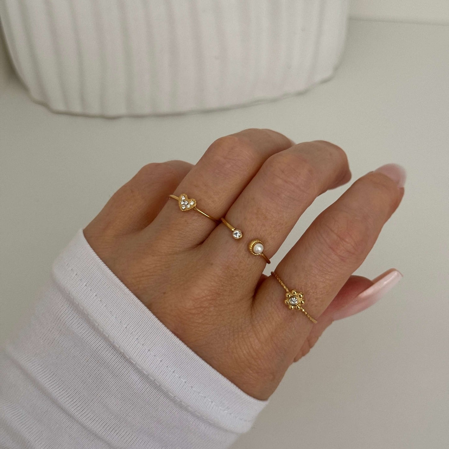 A set of three adjustable dainty rings featuring a flower, a pearl, and a heart, created by Kataleya.