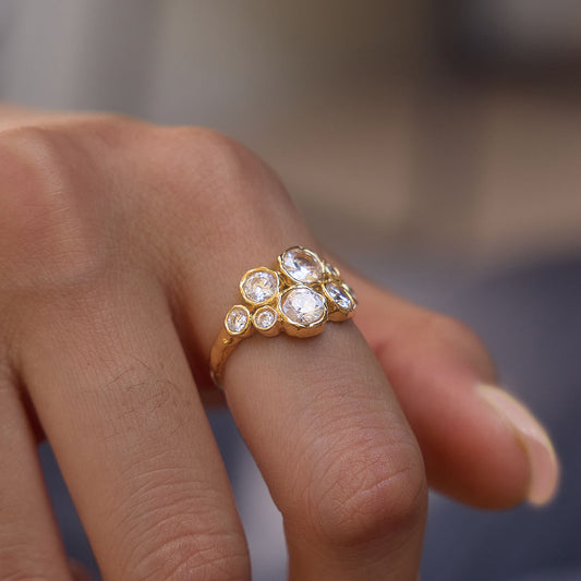 Astra Cluster Ring featuring eight round cubic zirconia in gold bezels, worn on a hand.
