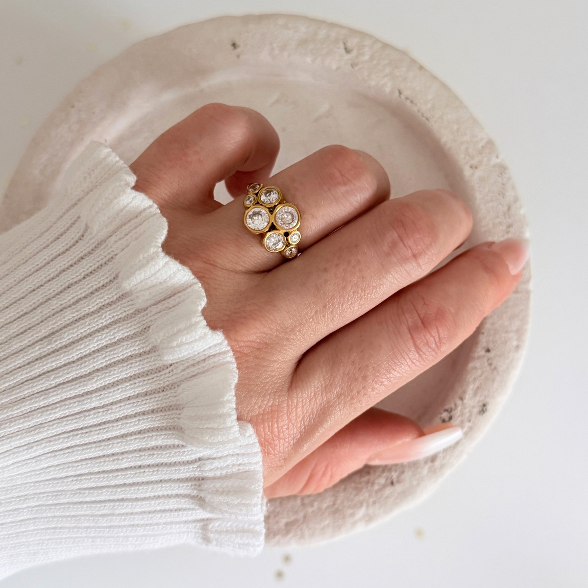 Close-up of a hand wearing an Astra Cluster Ring featuring cubic zirconia in a gold setting.