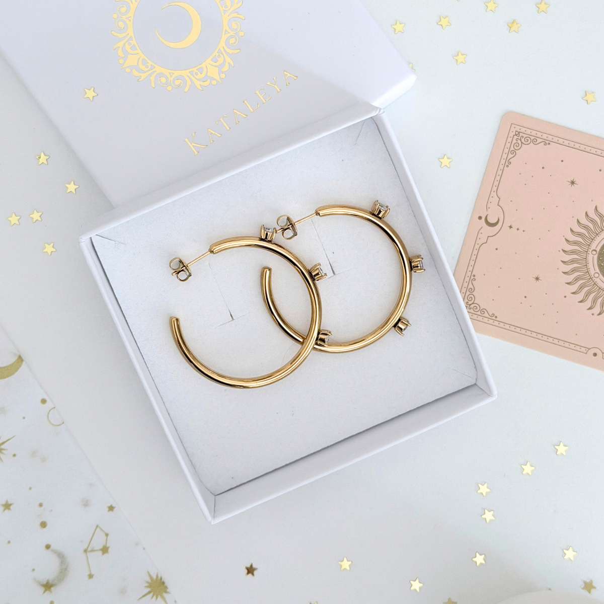 Callisto Crystal Hoops in gold plated stainless steel, featuring three round crystals, displayed in a box.