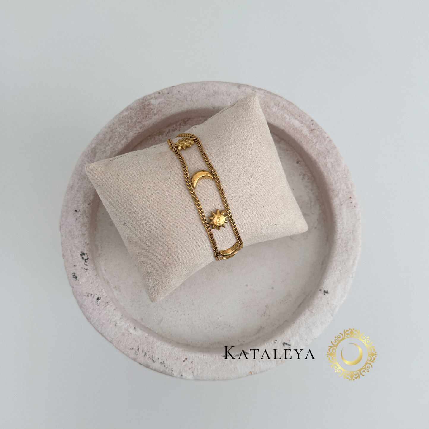 Celestial Harmony Bracelet displayed on a soft cushion, featuring sun and moon charms in gold.