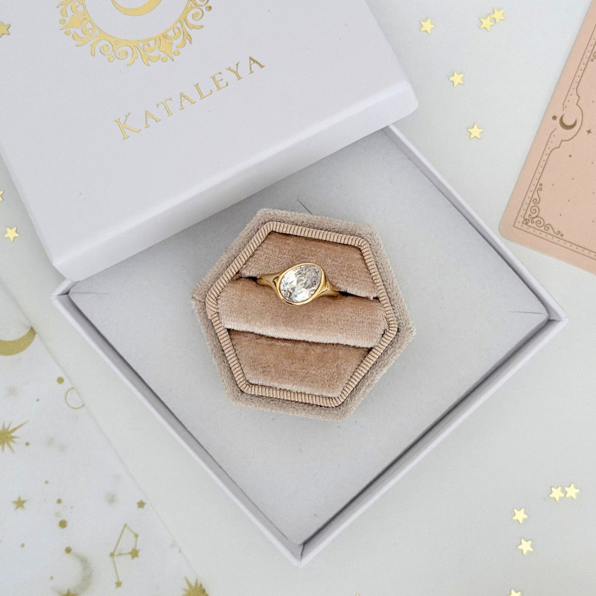 Elara Pinky Ring featuring an oval cubic zirconia set in gold, displayed in a stylish hexagonal jewelry box.