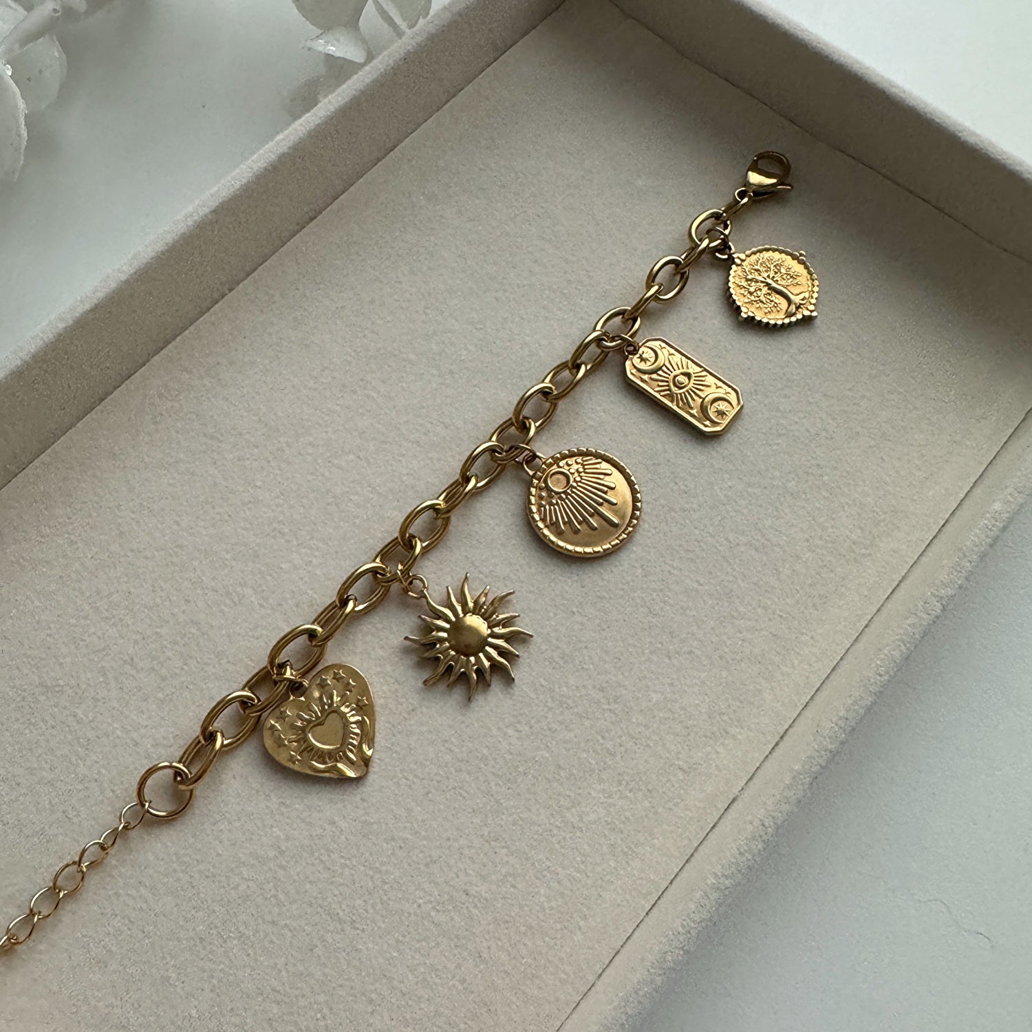 The Spirit Multi Charm Bracelet, adorned with five gold charms, symbolizes love, the sun, a star, an eye flanked by two moons, and a tree - all from Kataleya.