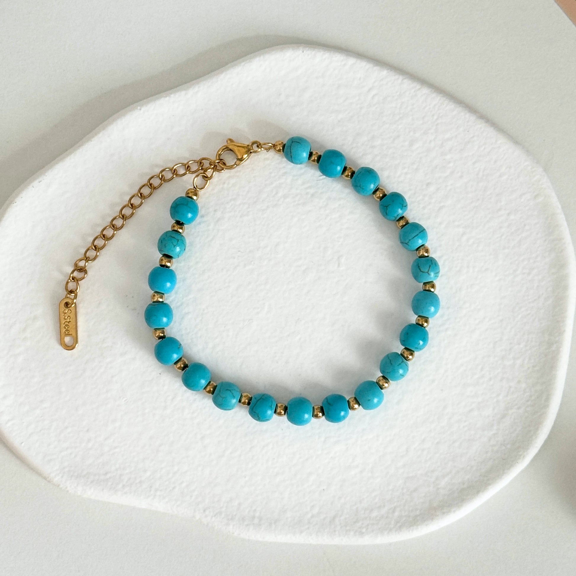 Waterproof Bracelet featuring delicate turquoise beads and gold accents on a soft white background.