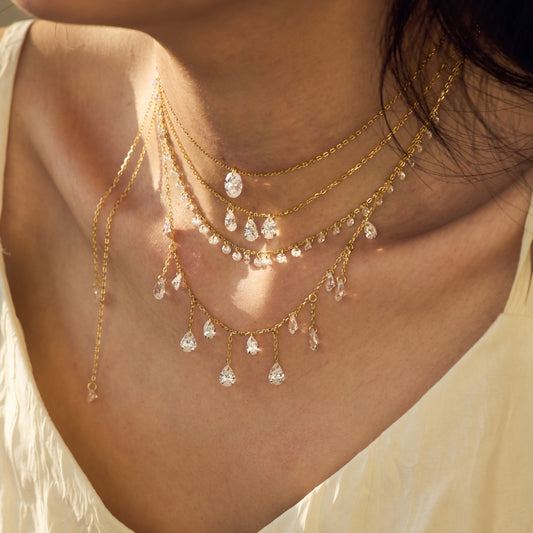 Gold Seraphine Celestia necklace with diamond pendants on a person wearing a light-colored top by Kataleya Jewellery