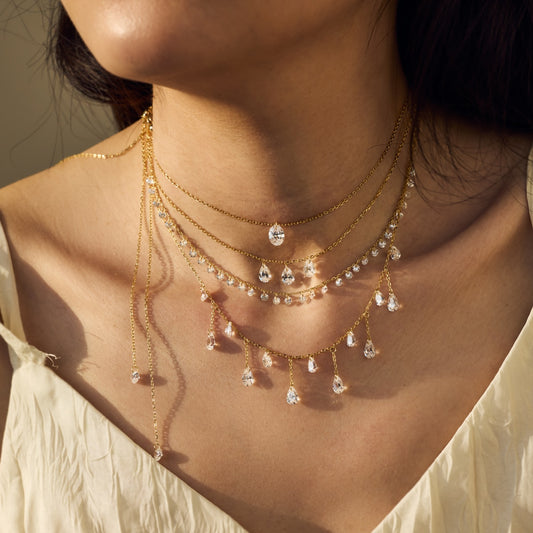 Close-up of a woman wearing a delicate gold Seraphine Celestia necklace with teardrop-shaped pendants by Kataleya Jewellery
