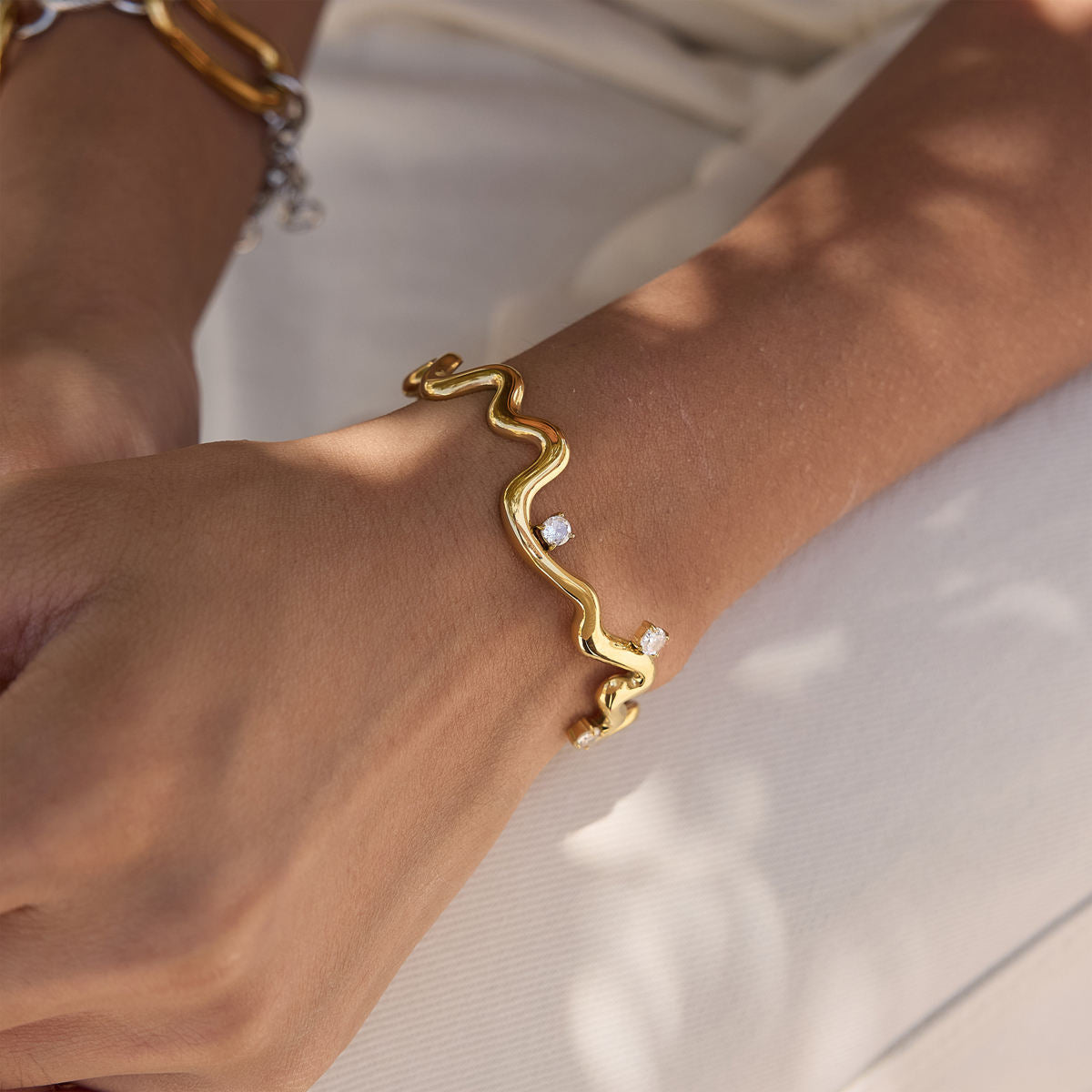 Thalia Squiggle Cuff on a wrist featuring three round crystals, crafted from gold plated stainless steel.